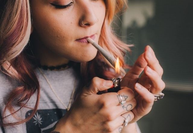 A young woman smoking pot from a cannabis cigarette.