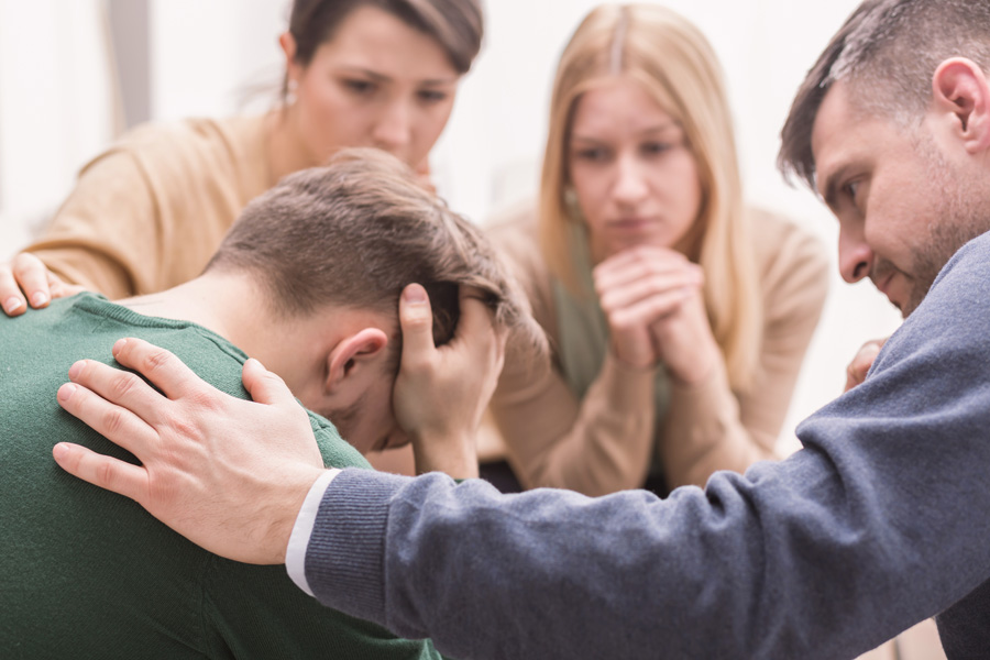 Teenage boy with head in his hands and parents consoling him