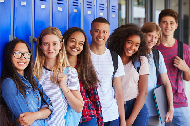 Teenagers in a recovery high school standing together near some lockers.
