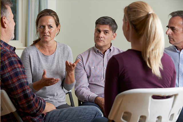 Adults sitting in a close circle and a woman talking to her daughter.