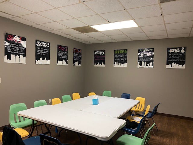 3 tables pushed together with chairs around it, pictures of the steps on the walls