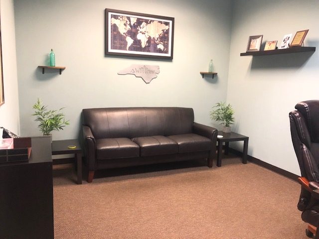 office with a brown leather couch and wall decor