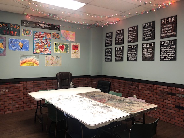 room with table and chairs with posters on the walls and Christmas lights hanging from the ceiling.