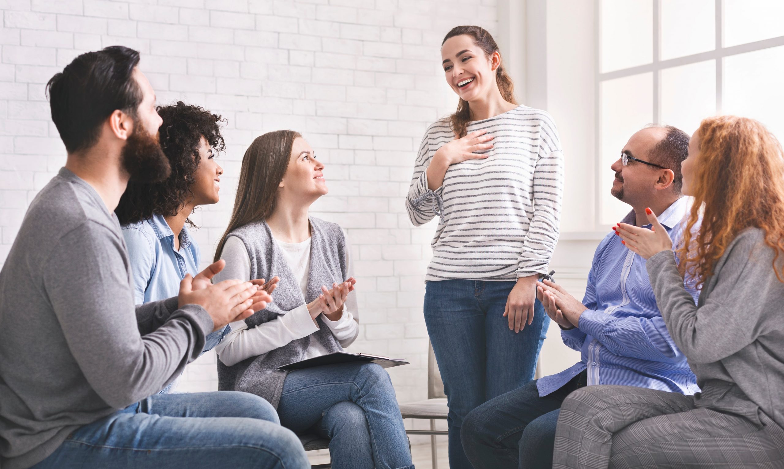 A sober young girl sharing in a support group meeting.