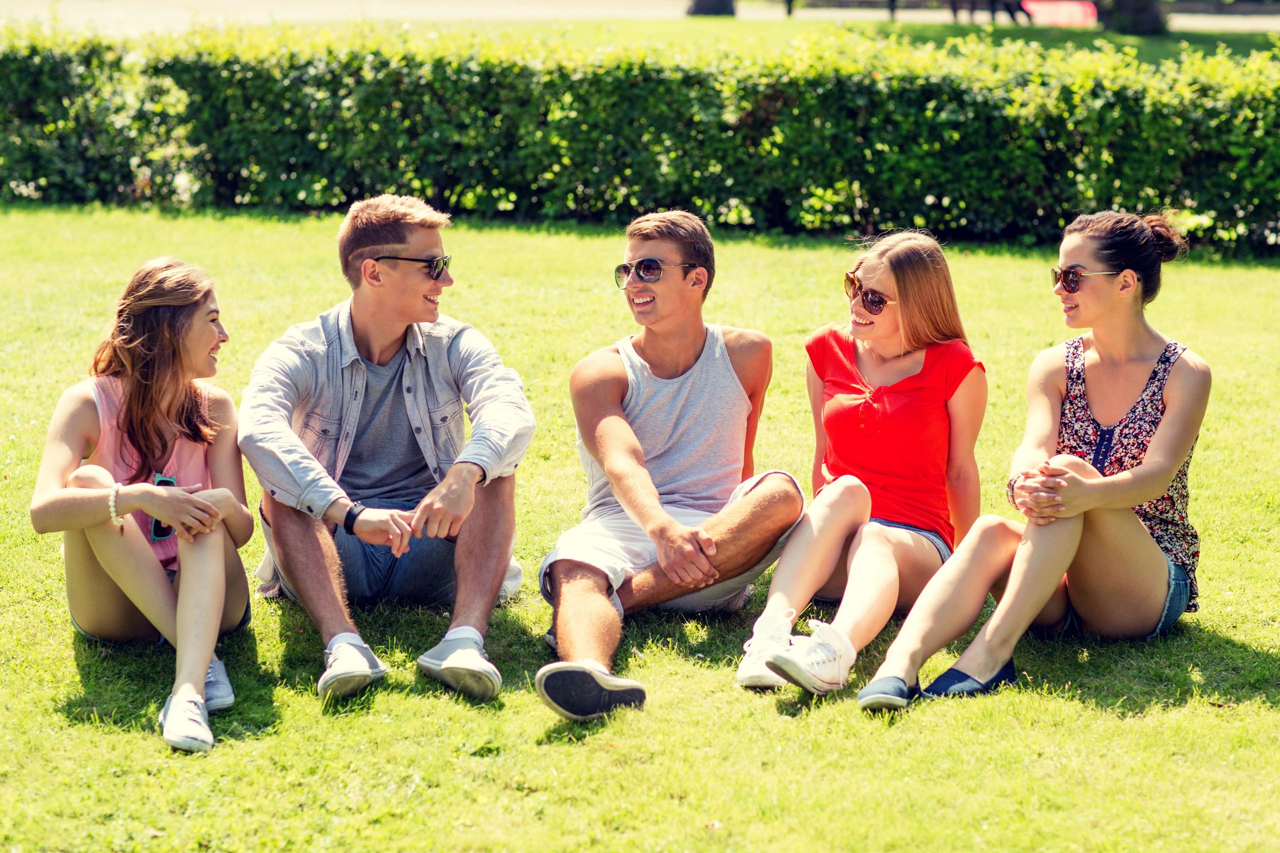 Young people in recovery sitting together on a lawn.