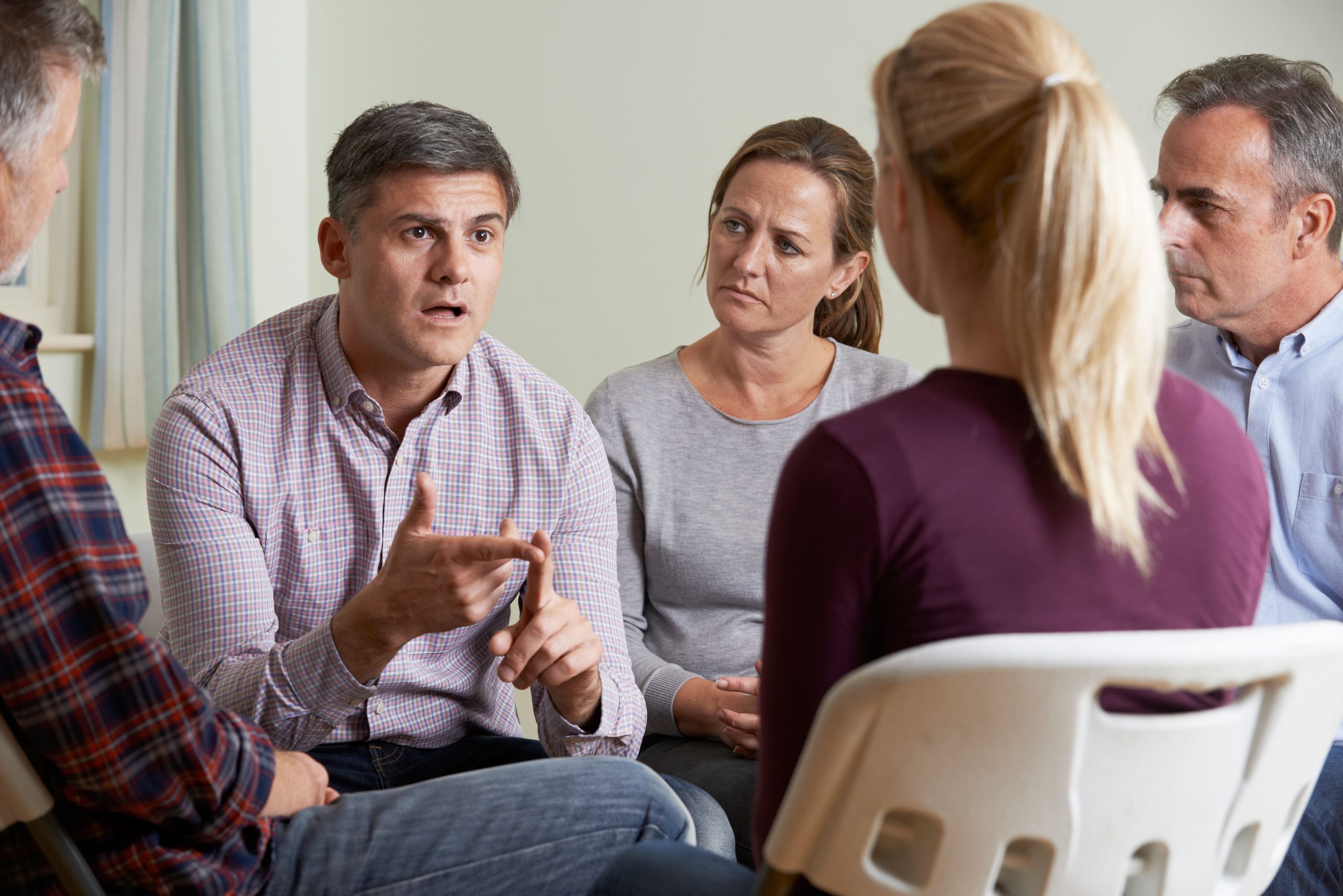 adults sitting in a close circle with a man talking to a woman