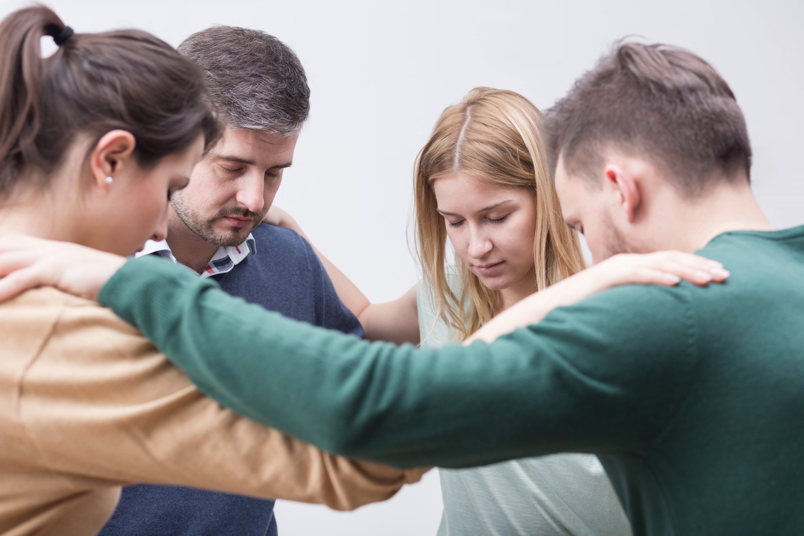 A group of young people in sobriety praying together.