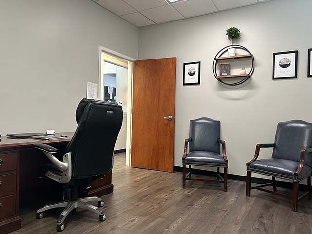 a picture of an office with a desk and 2 chairs