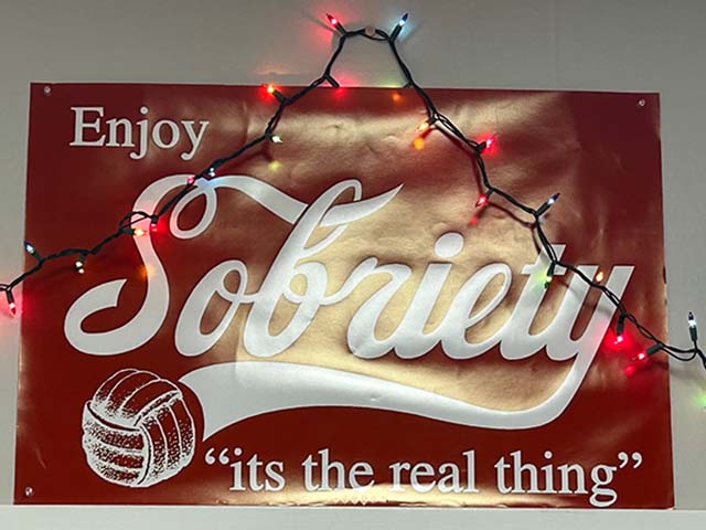 a red poster that says sobriety with Christmas lights