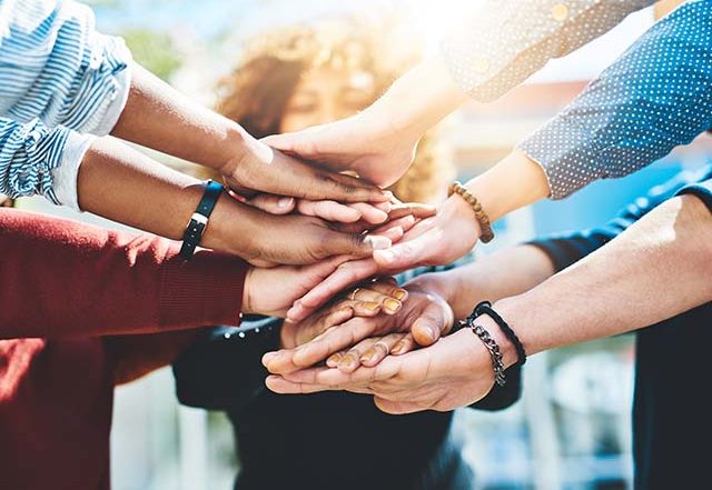Parents in a support group stacking hands to support one another.