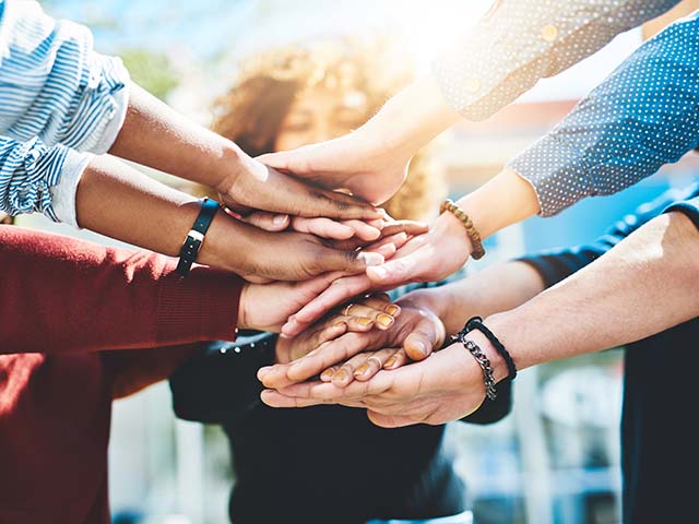 Parents in a support group stacking hands to support one another.